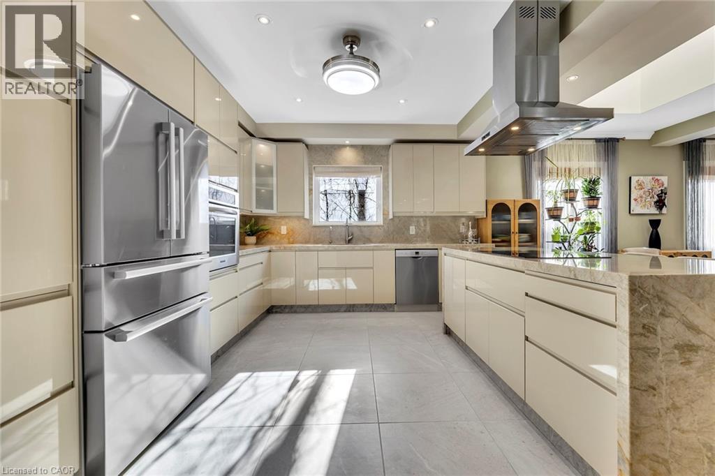 Contemporary kitchen featuring a large center island with stone countertops, glossy cream cabinetry, stainless steel appliances, and recessed lighting