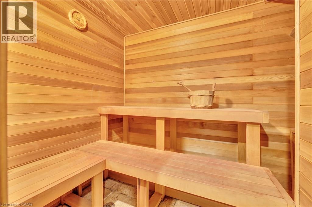 Interior sauna with light wood paneling, multi-level wood benches, and a built-in circular wall thermometer