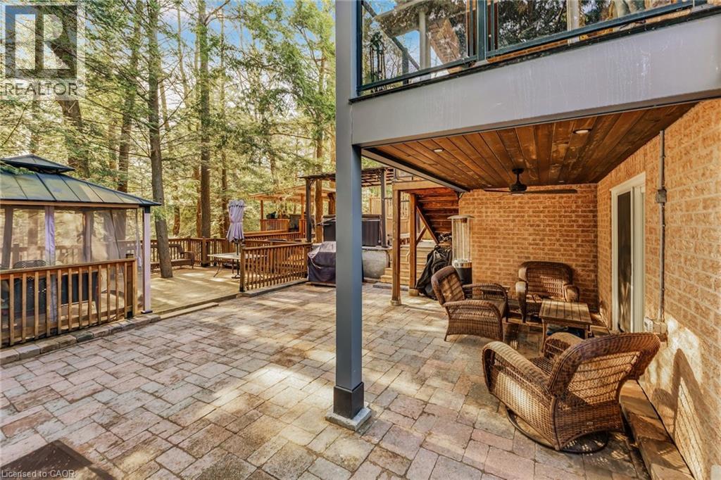 Expansive paver patio with a covered outdoor living area featuring a wood-finish ceiling and a ceiling fan