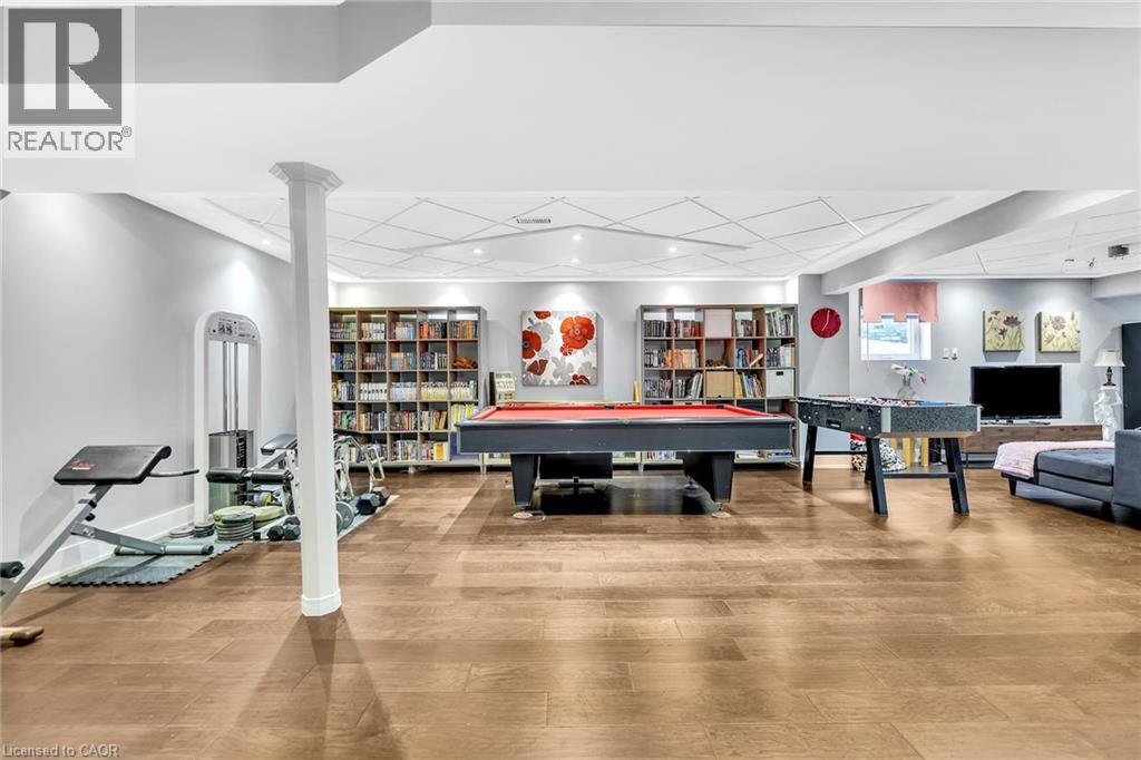 Expansive recreation room featuring wood-finish flooring, recessed lighting, and built-in shelving