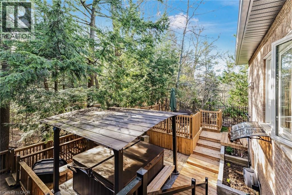 Multi-level wooden deck featuring a covered hot tub, built-in wooden planters, and a brick exterior with white-framed windows