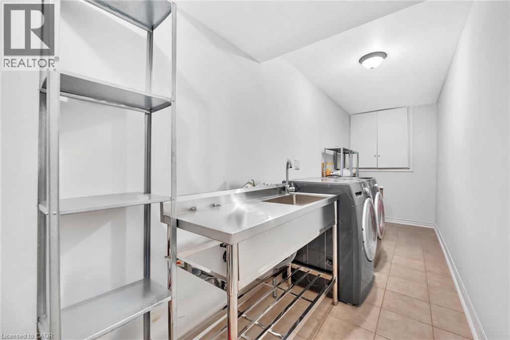 Utility room featuring a stainless steel sink with integrated faucet, tile flooring, and overhead flush-mount lighting