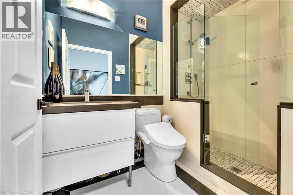 Modern bathroom featuring a glass-enclosed shower with a rainfall showerhead, a floating vanity with a dark countertop, a wall-mounted faucet, and a contemporary toilet