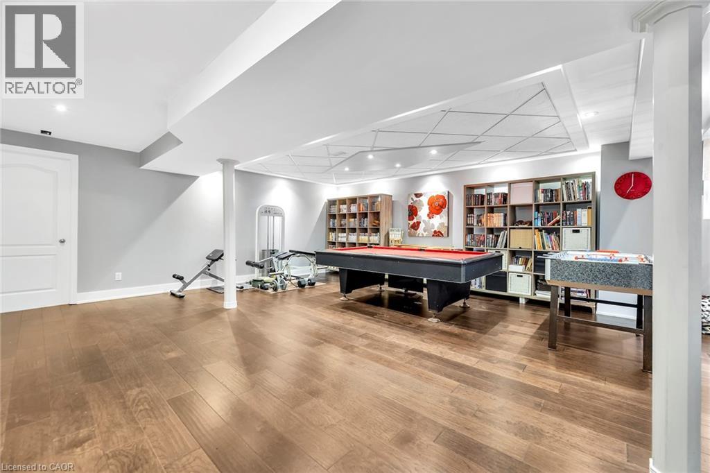 Spacious lower-level area featuring wood-finish flooring, recessed lighting, and a tray ceiling with decorative paneling