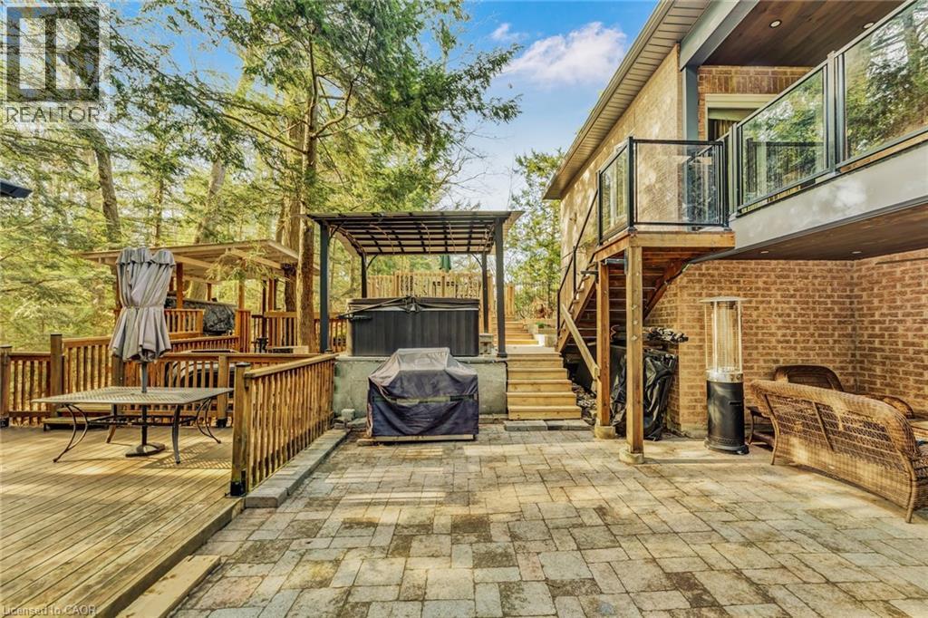 Multi-level outdoor living space featuring a wooden deck with railing, a paver patio, and a covered hot tub area