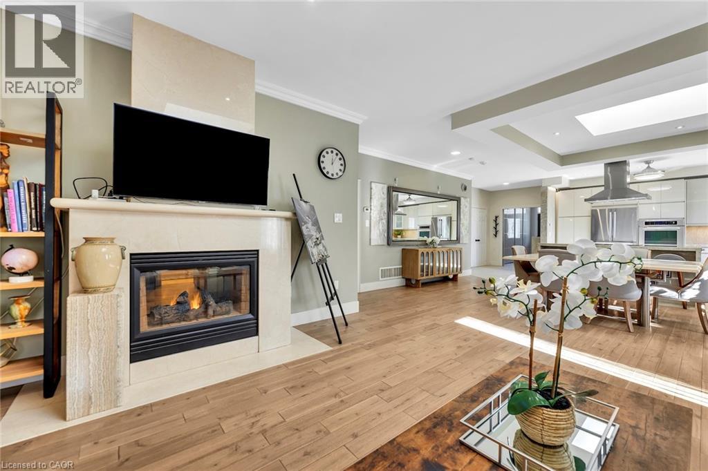 Living space featuring wood-finish flooring, a contemporary fireplace with a stone surround, recessed lighting, crown molding, and an open concept layout