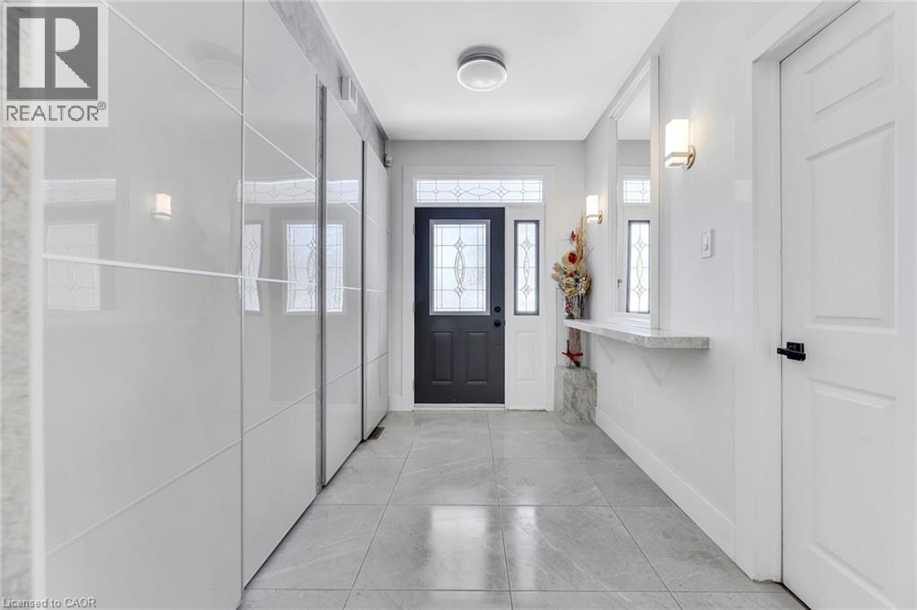 Foyer featuring a dark-paneled entry door with decorative glass, a transom window, and an adjacent sidelight