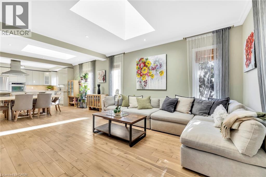 Open-concept living area featuring light wood-finish flooring, recessed lighting, and a skylight