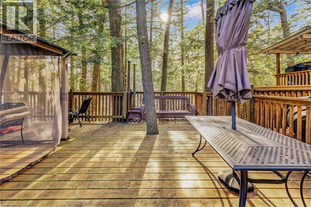 Spacious wood-plank deck featuring natural wood railing and mature surrounding trees