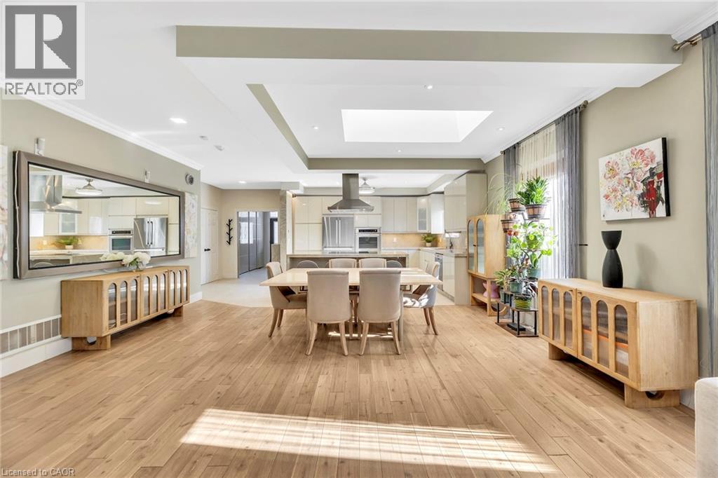 Open-concept living space featuring wood-finish flooring, recessed lighting, a skylight, crown molding, and a kitchen with stainless steel appliances