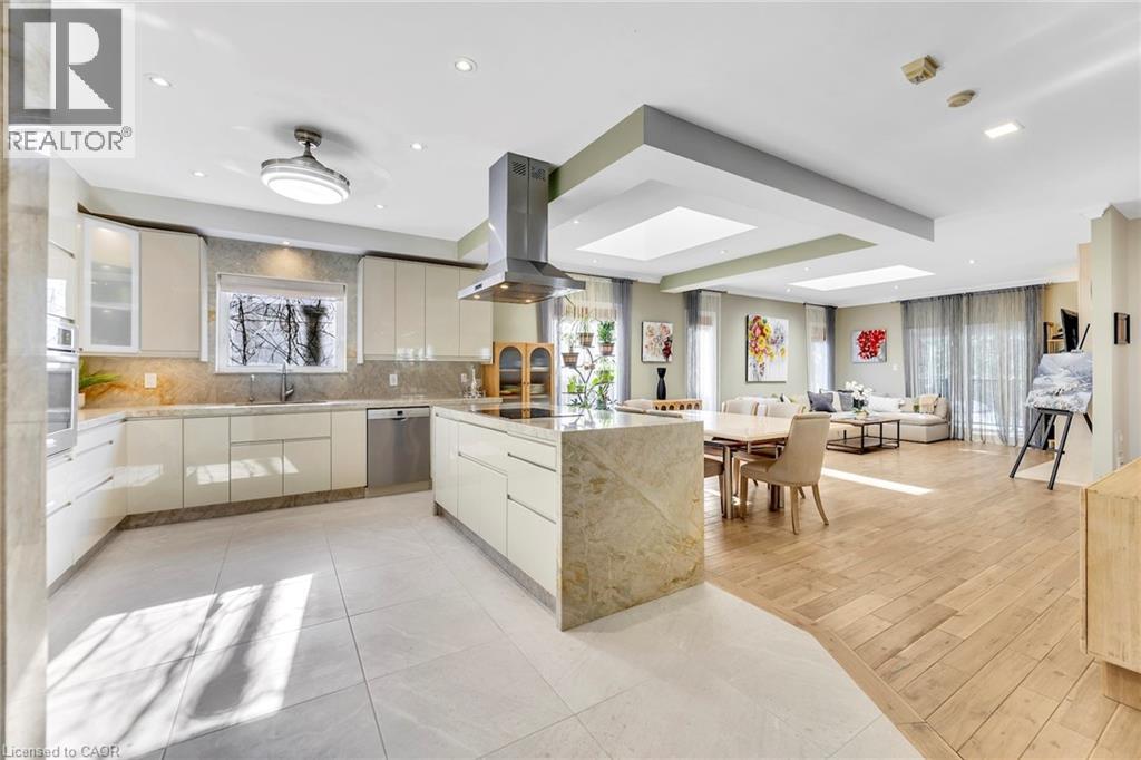 Contemporary kitchen featuring cream cabinetry, stainless steel appliances, and a central island with integrated cooktop