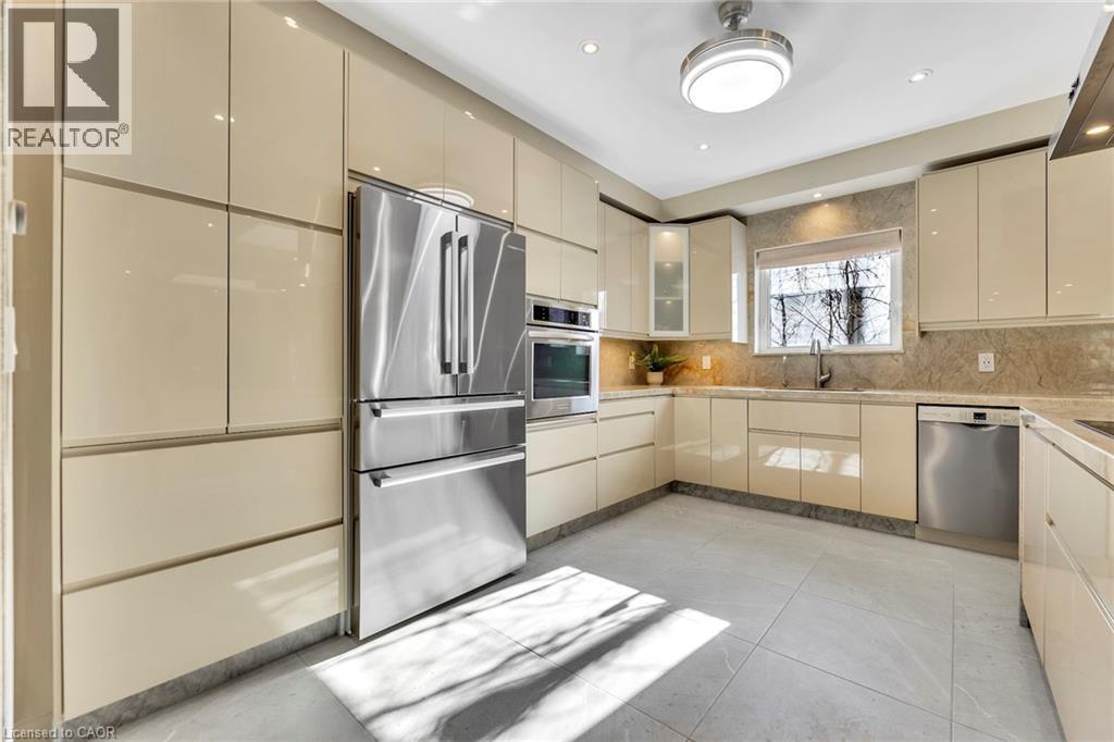 Modern kitchen featuring light-toned cabinetry, stainless steel appliances, a built-in oven, recessed lighting, and a window above the sink