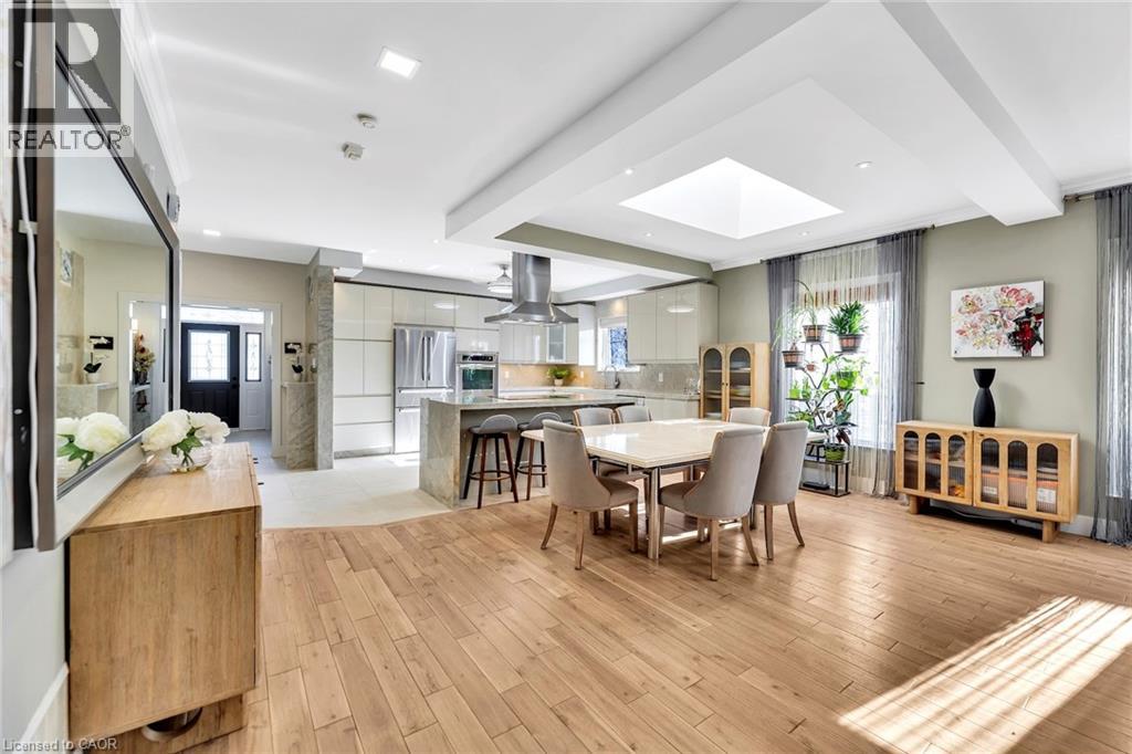 Open-concept living space featuring wood-finish flooring, a kitchen island with seating, stainless steel appliances, a square skylight, and recessed lighting
