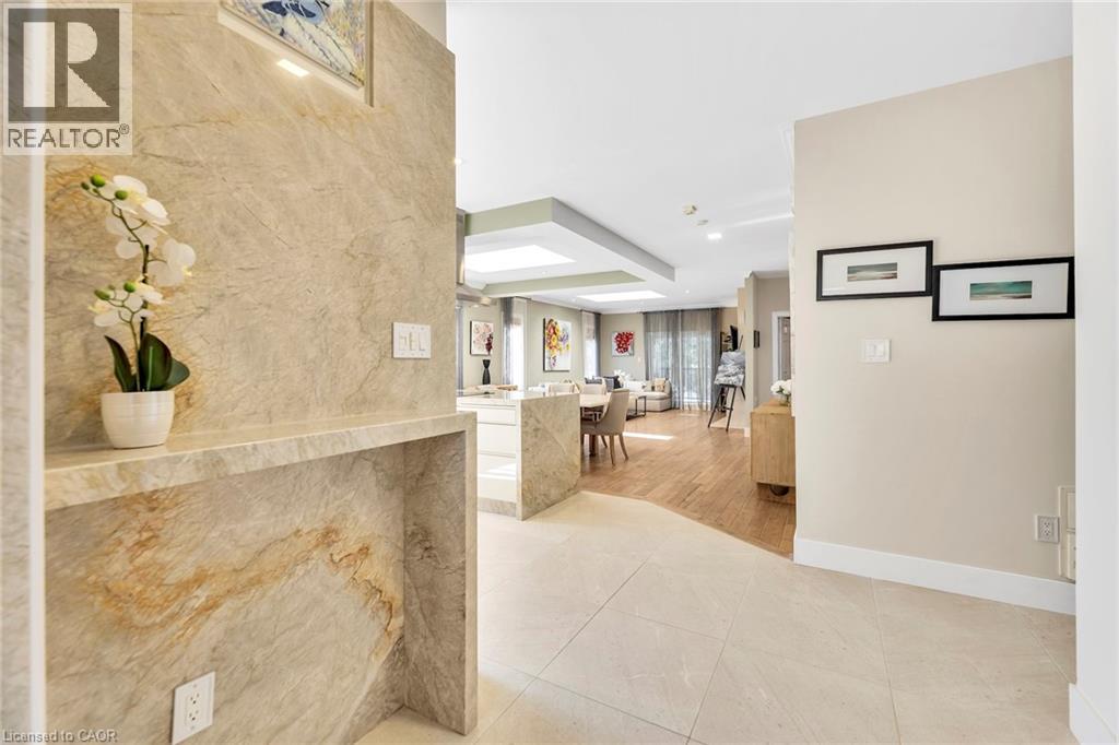Entryway featuring large format tile flooring, a stone accent wall with integrated shelf, recessed lighting, and a sightline into the main living areas with wood-finish flooring