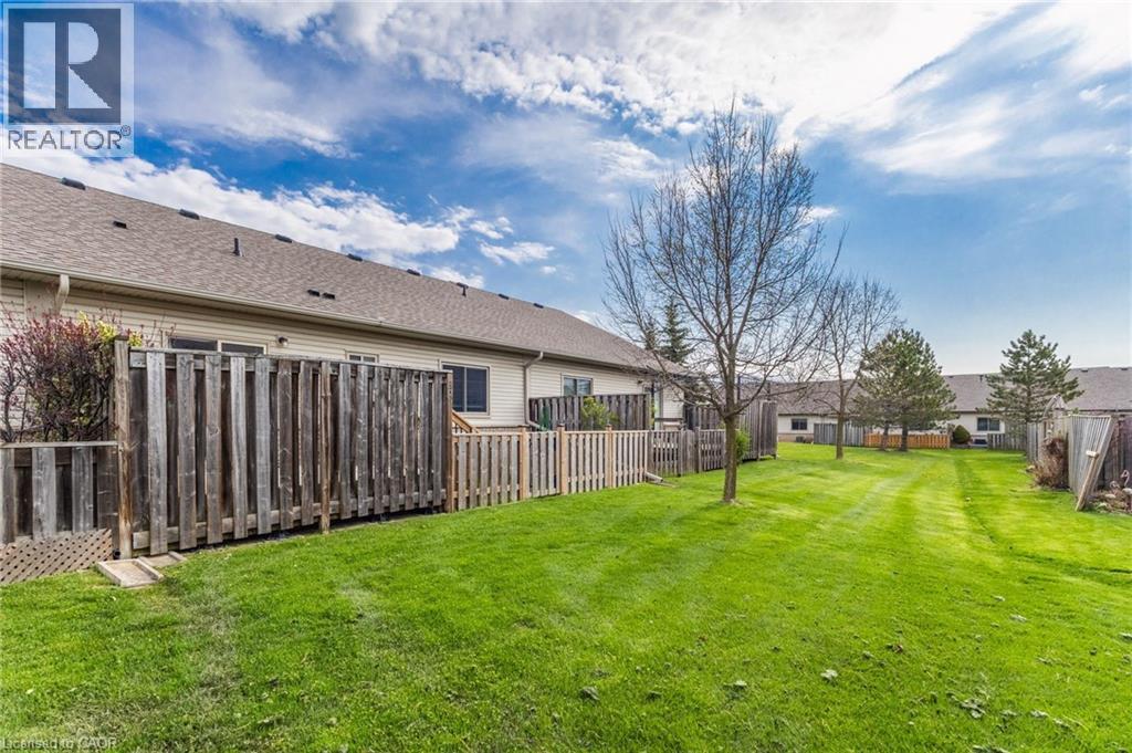 Expansive rear yard featuring a manicured lawn, established trees, and wood fencing