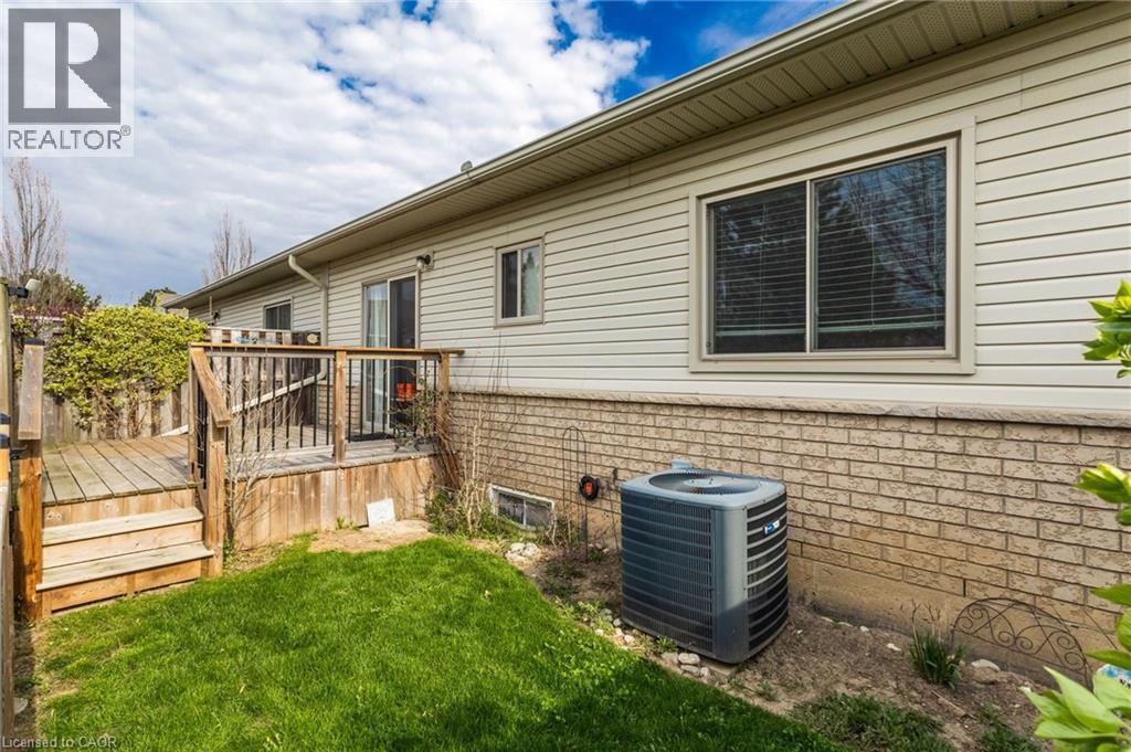 Rear exterior featuring beige siding, a brick foundation, a sliding glass door, and an elevated wood deck with stairs