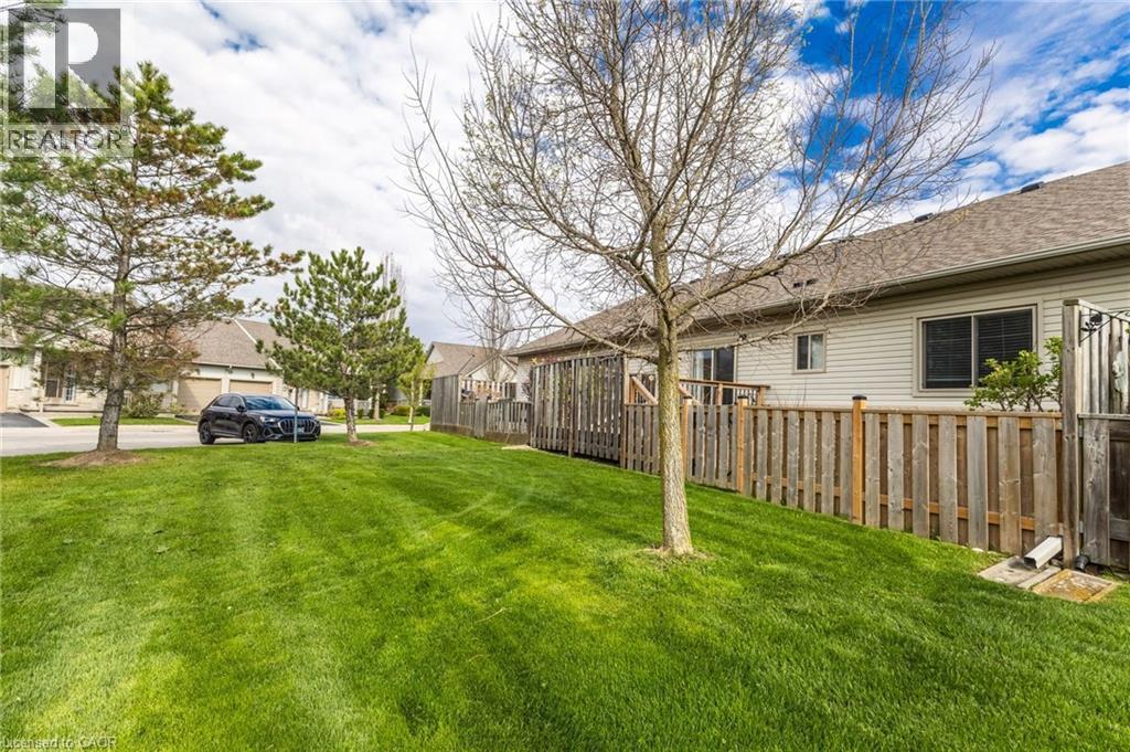 Expansive green lawn with mature trees and a wooden privacy fence