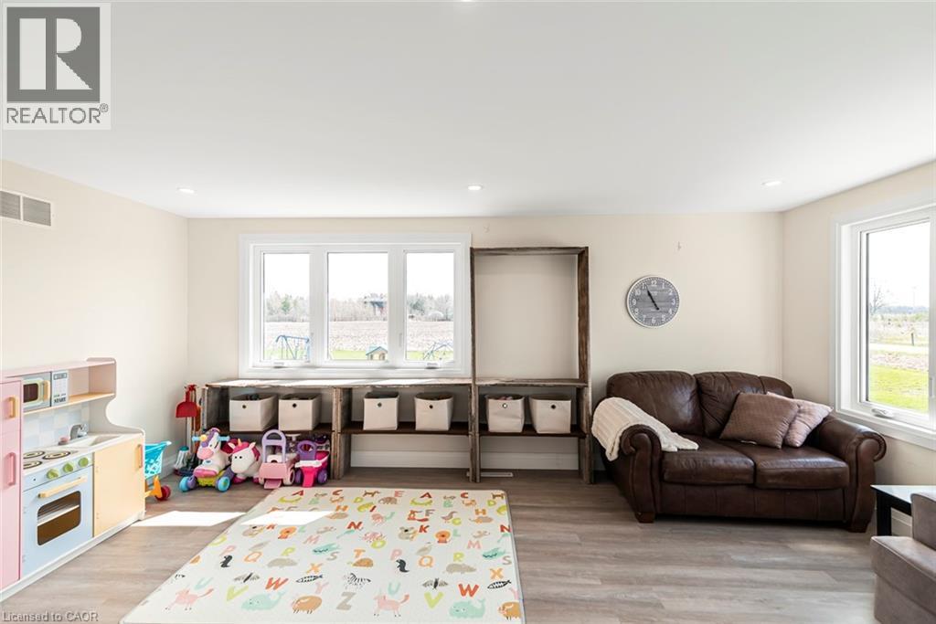 Light-filled room featuring multiple windows, recessed ceiling lighting, light-toned wall paint, wood-finish flooring, and a built-in shelving unit