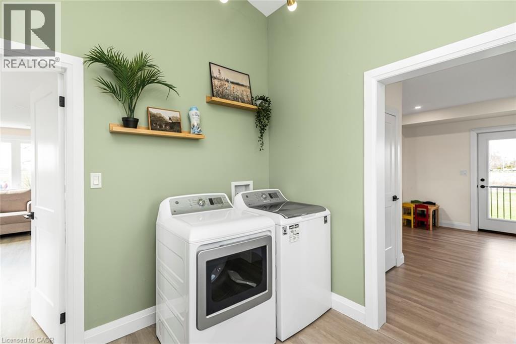 Dedicated laundry area featuring light green walls and wood-finish flooring