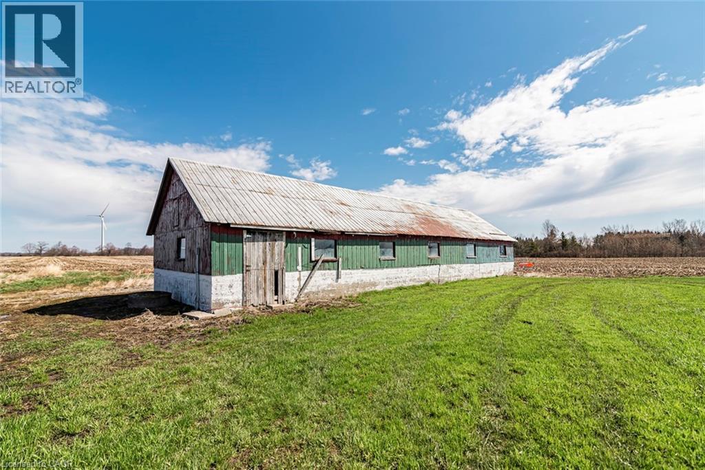 Barn structure featuring a metal roof, green and natural wood siding, and a white foundation