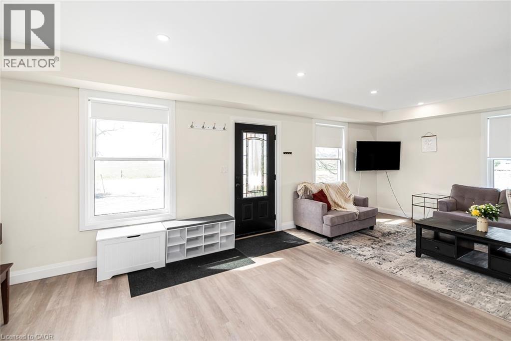 Spacious living area featuring light wood-finish flooring, white trim, recessed lighting, and a black paneled entry door with decorative glass inserts