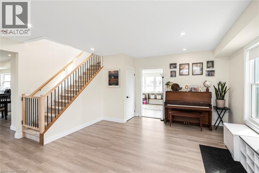Open-concept living area featuring wood-finish flooring, recessed lighting, and a prominent staircase with wood handrails and black metal balusters