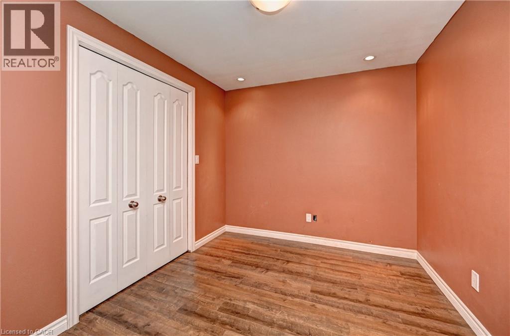 Room featuring wood-finish flooring, recessed lighting, white baseboards, and a bi-fold closet door with paneled detailing