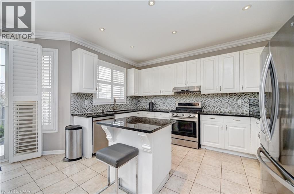 Kitchen featuring white cabinetry, dark countertops, mosaic tile backsplash, stainless steel appliances, and a central island with a breakfast bar