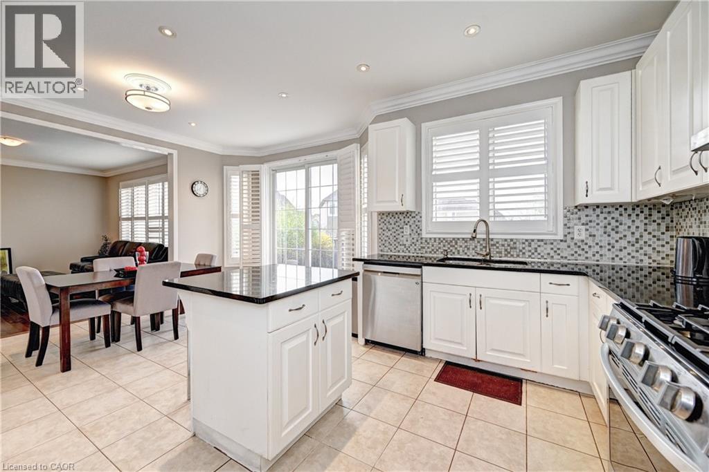 Bright kitchen featuring white cabinetry, black countertops, stainless steel appliances, and a mosaic tile backsplash
