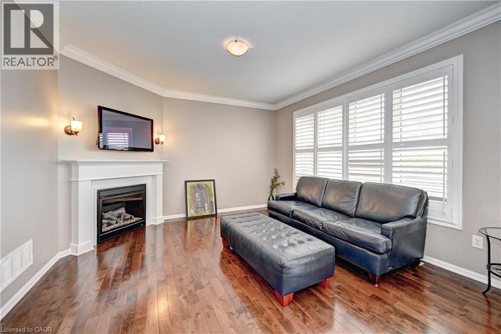 Living area featuring wood-finish flooring, a white mantel fireplace, and wall sconces