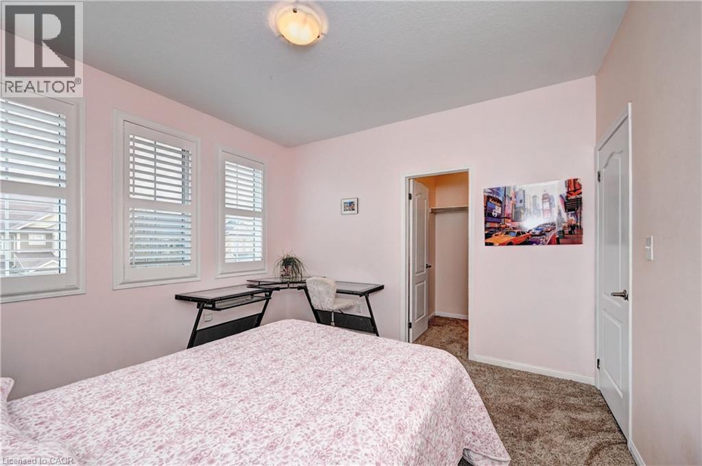 Room featuring three windows with plantation shutters, a corner desk, a closet with a bi-fold door, and carpet flooring