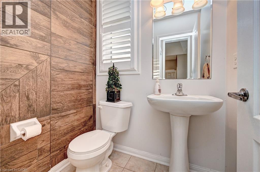 Powder room featuring a pedestal sink, wood-finish accent wall, white window shutters, and a mirror with overhead vanity lighting