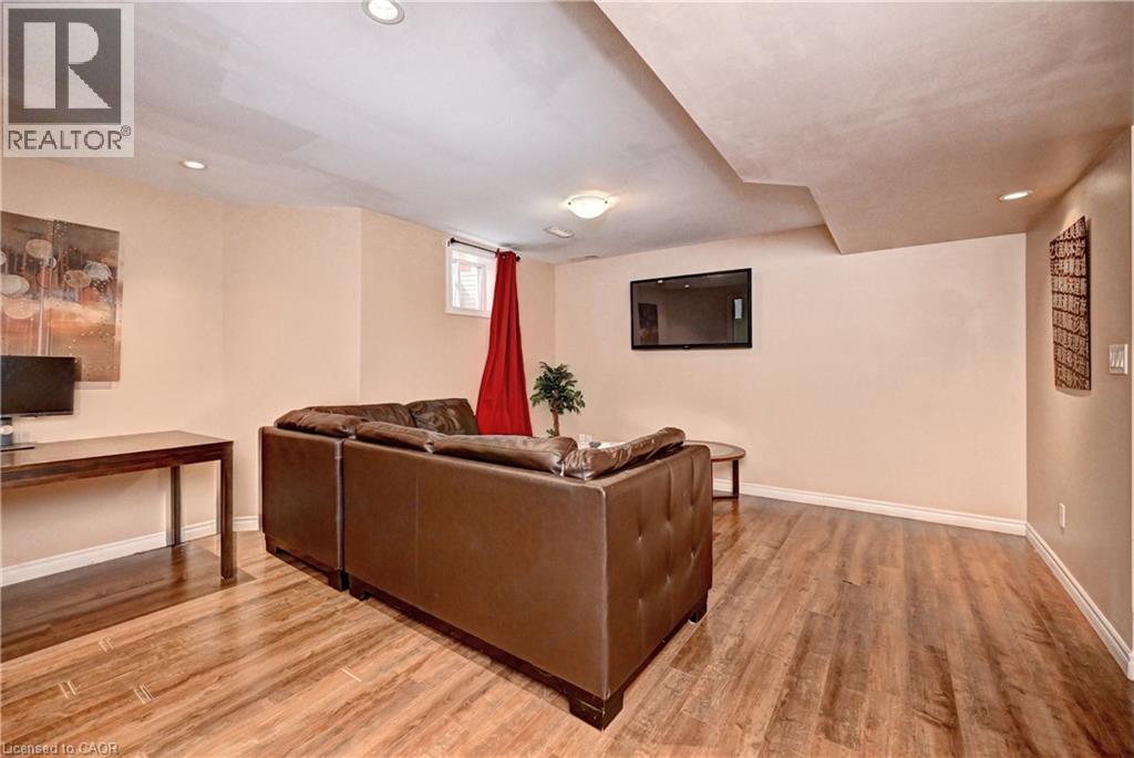 Spacious lower-level area featuring wood-finish flooring, recessed lighting, and a built-in wall-mounted television