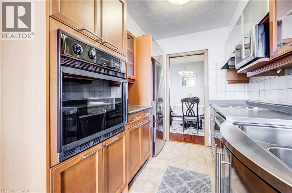 Kitchen featuring stainless steel appliances, wood finish cabinets, glass insert cabinets, a textured ceiling, and light tile patterned floors