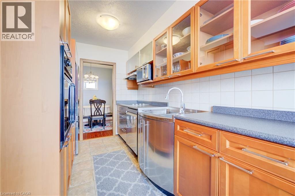 Kitchen featuring decorative backsplash, glass fronted cabinets, stainless steel appliances, wood finish cabinetry, and a textured ceiling