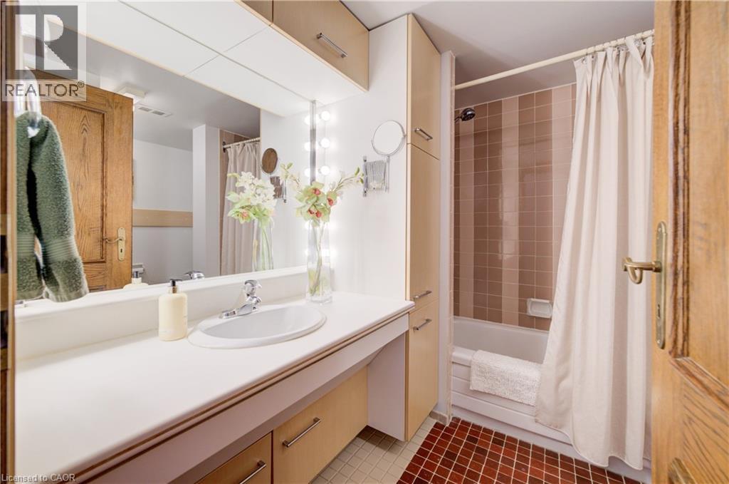 Bathroom with vanity, shower / bath combination with curtain, and dark tile patterned flooring