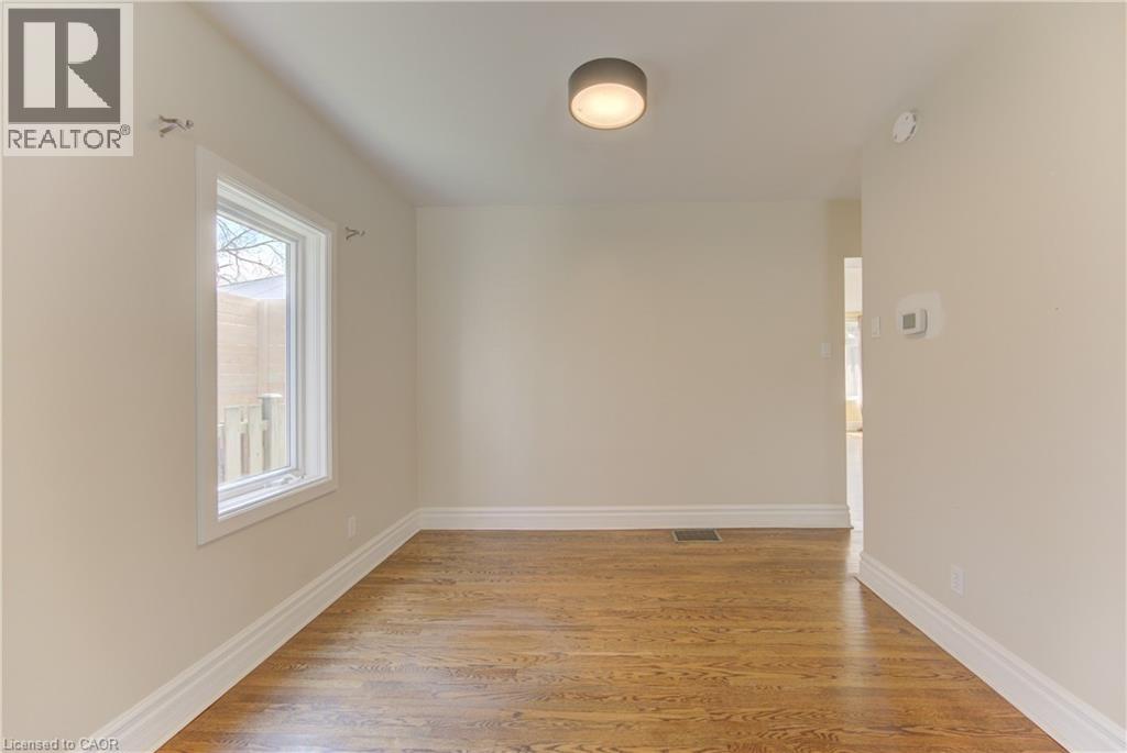 Light-filled interior space featuring wood-finish flooring, white baseboards, and a single window