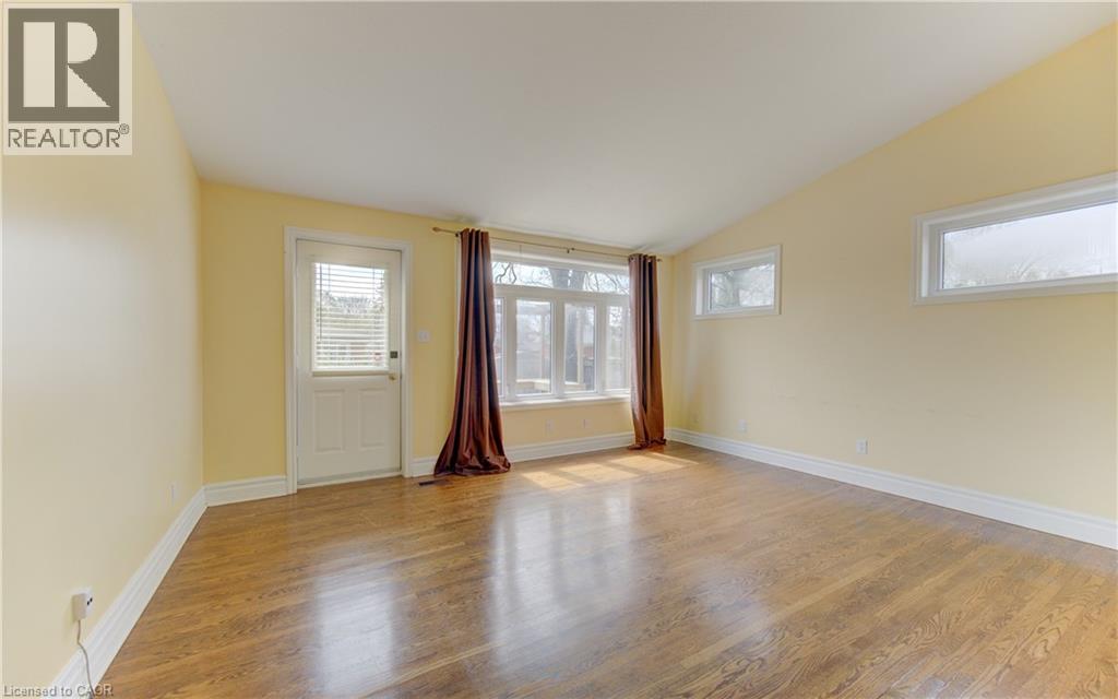 Spacious room featuring wood-finish flooring, vaulted ceiling, and multiple windows