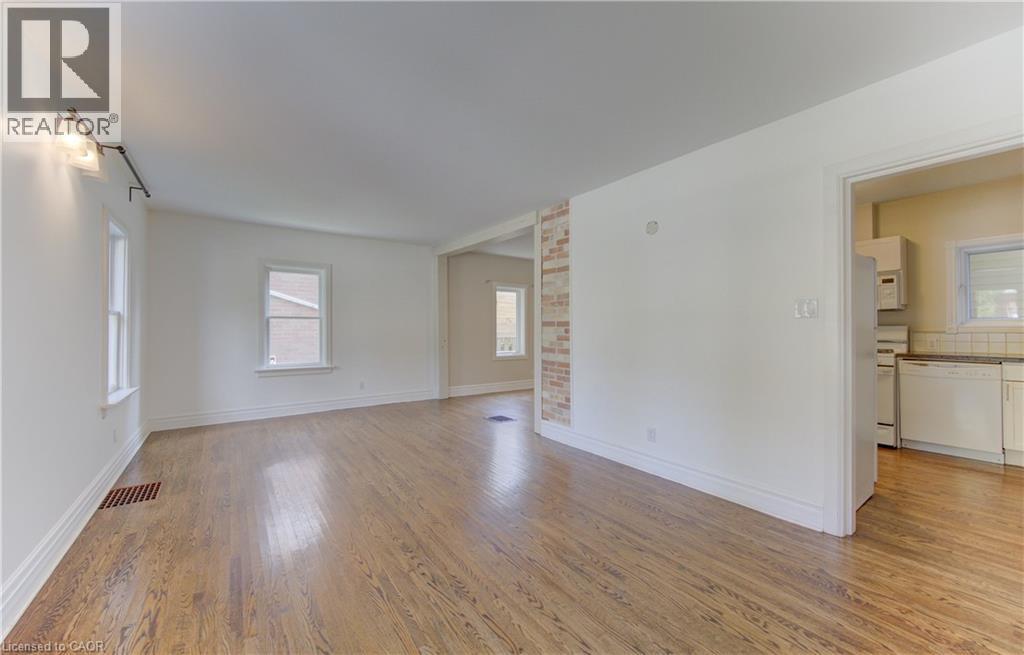Spacious room featuring wood-finish flooring, white baseboards, and white walls