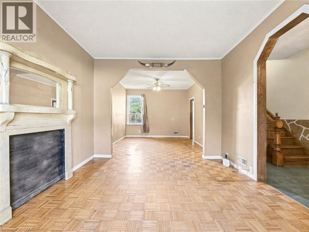 Unfurnished living room with crown molding, arched walkways, a ceiling fan, a fireplace, and stairs