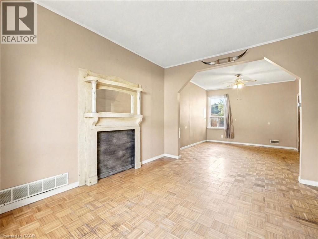Unfurnished living room with arched walkways, ornamental molding, and a ceiling fan