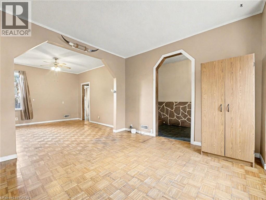 Empty room featuring ornamental molding, arched walkways, and a ceiling fan