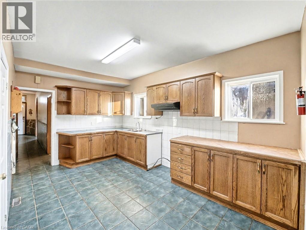 Kitchen featuring open shelves, backsplash, brown cabinets, and healthy amount of natural light
