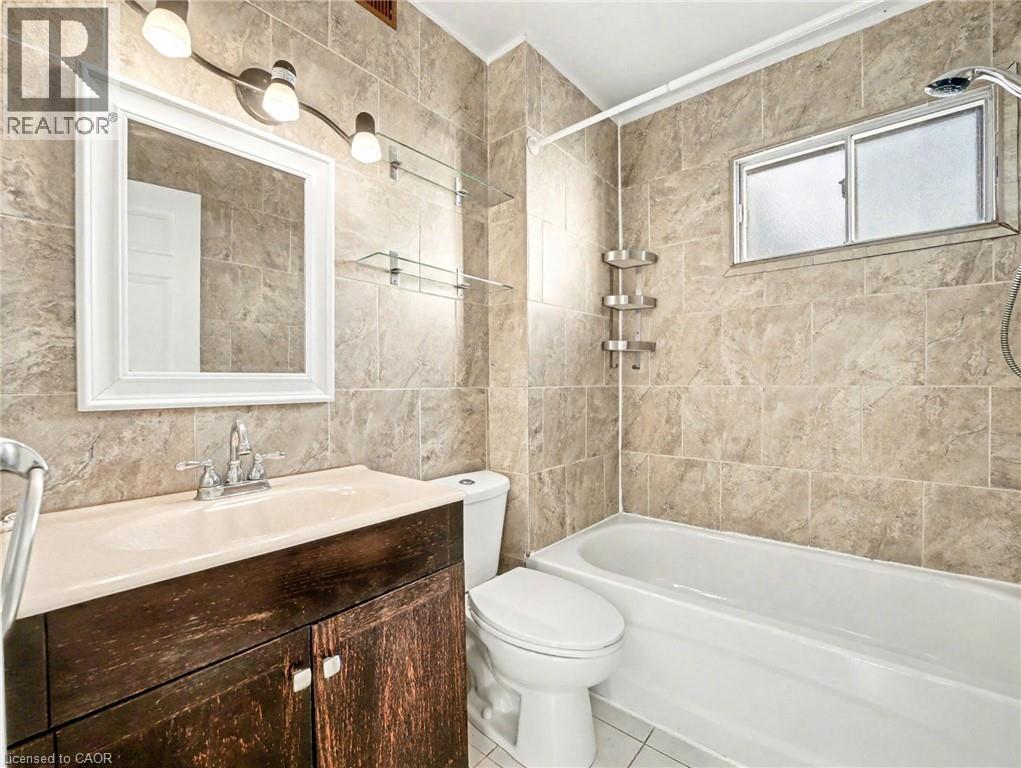 Bathroom with tile walls, shower / bathtub combination, vanity, and tile patterned flooring