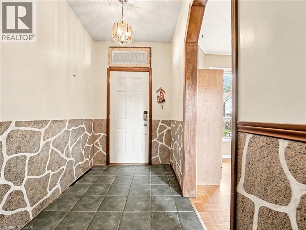 Entryway featuring dark tile patterned flooring, a chandelier, and a wainscoted wall