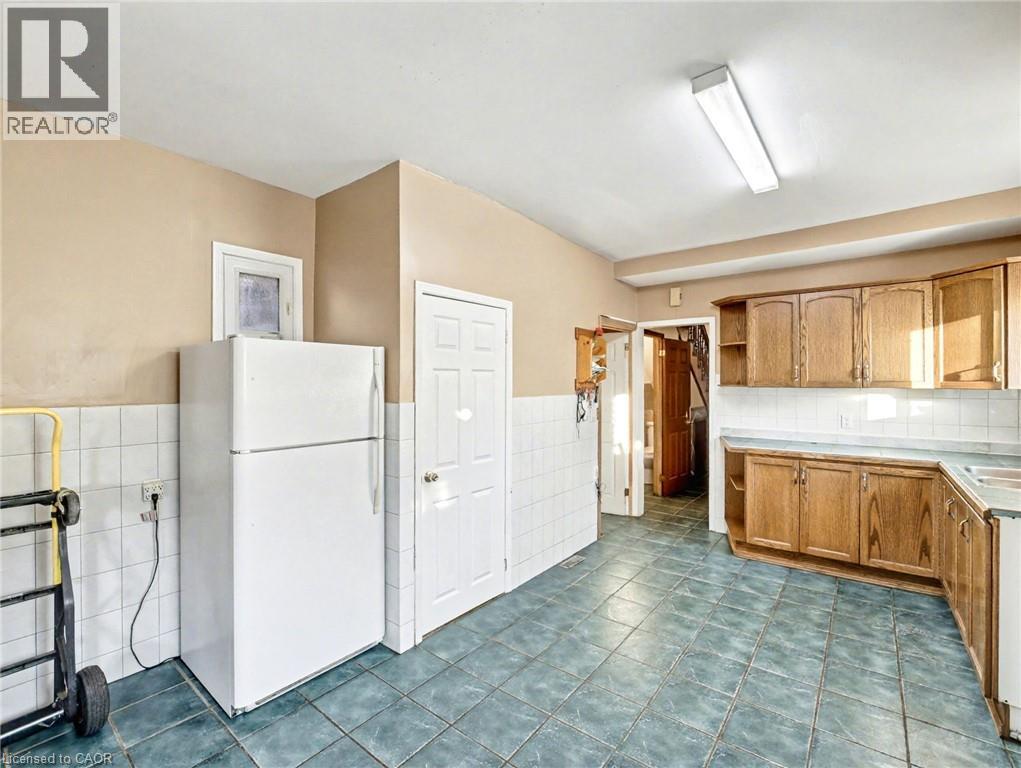 Kitchen featuring freestanding refrigerator, open shelves, tile counters, dark tile patterned floors, and tile walls