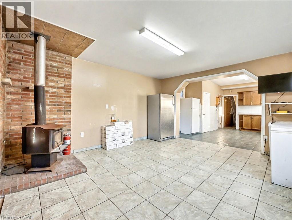 Kitchen with light tile patterned floors, a wood stove, freestanding refrigerator, and light countertops