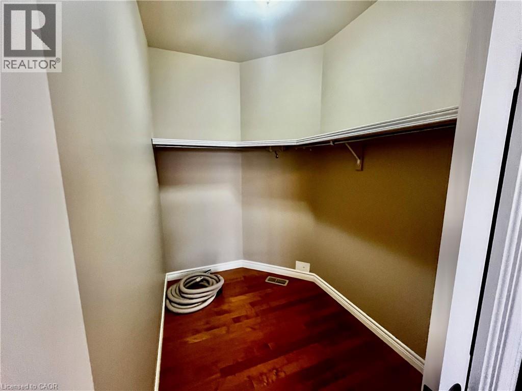 Walk-in closet featuring wood-finish flooring, built-in shelving