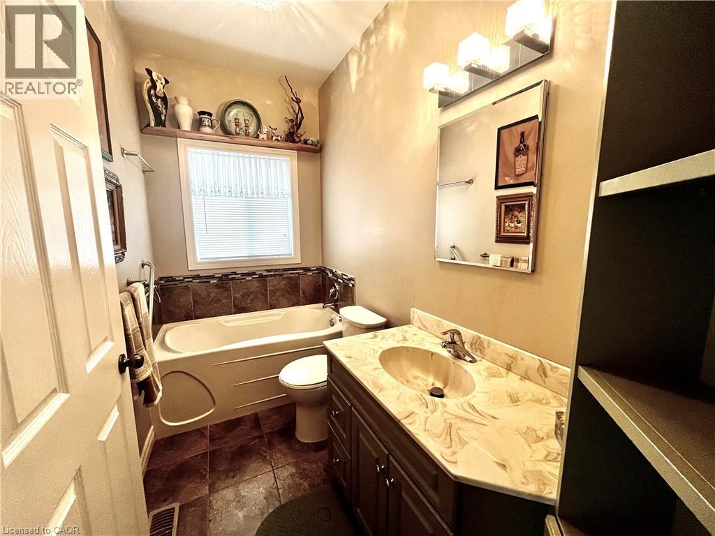 The bathroom features a vanity with a marbled countertop, a bathtub with a tiled surround, and tiled flooring
