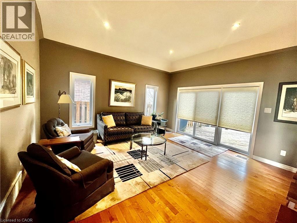 Living space featuring hardwood flooring, a vaulted ceiling, and sliding glass doors